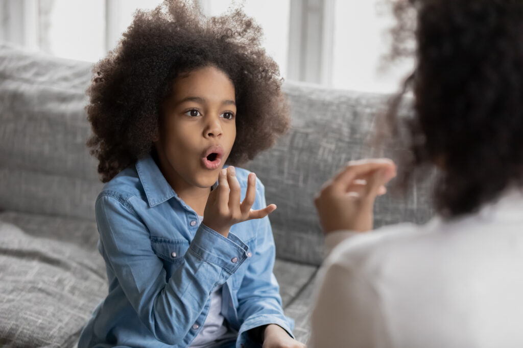 African American girl practicing sign language with a female Speech Therapist