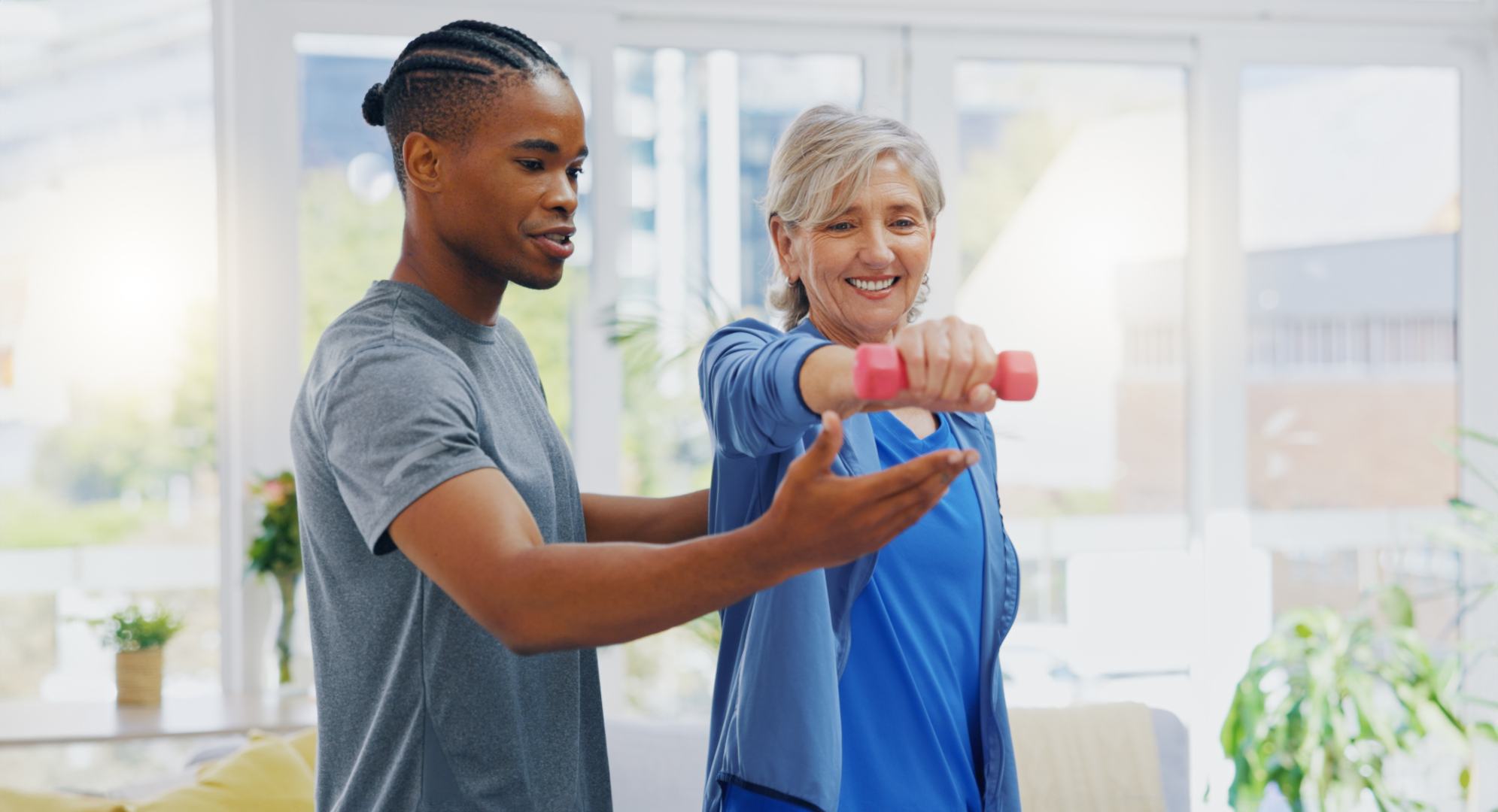 Male physiotherapist supporting a female patient to do exercises with dumbells